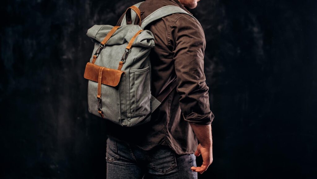 Man with stylish canvas backpack on dark background, back view. Close up
